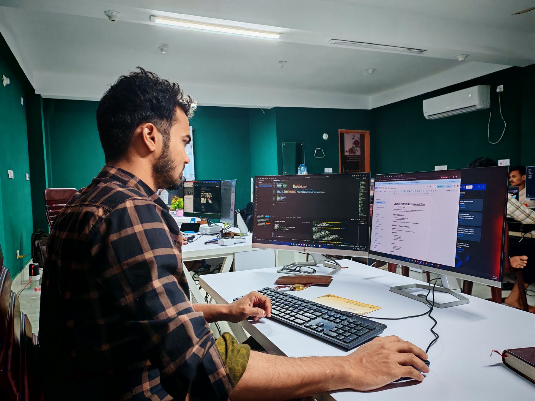 Software engineer working across code and operational documentation on multiple monitors